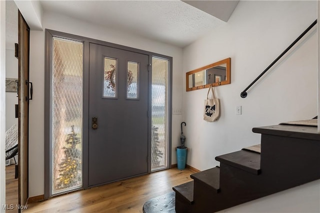 foyer featuring a textured ceiling, a healthy amount of sunlight, and light hardwood / wood-style floors