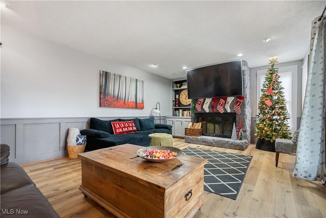 living room featuring light hardwood / wood-style floors and a stone fireplace