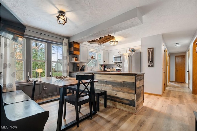 dining area featuring a textured ceiling and light wood-type flooring