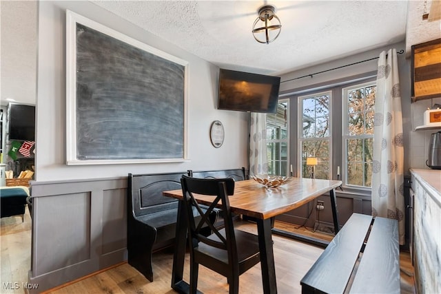 dining space with a textured ceiling and light hardwood / wood-style flooring