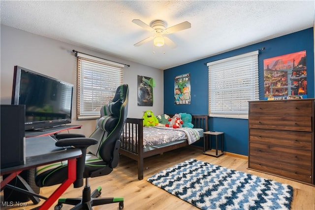 bedroom with ceiling fan, hardwood / wood-style floors, and a textured ceiling