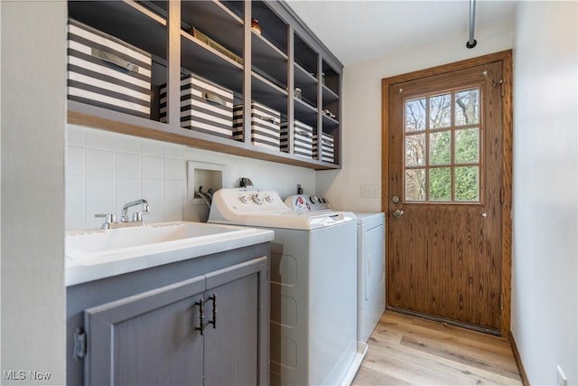 laundry room featuring cabinets, sink, independent washer and dryer, and light wood-type flooring