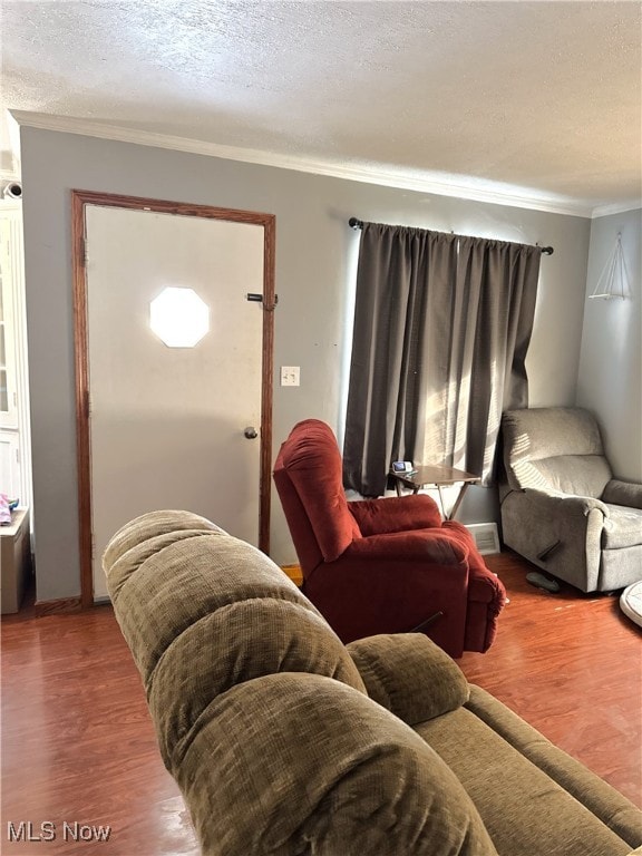 living room featuring wood-type flooring, a textured ceiling, and ornamental molding