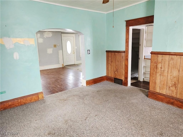 empty room featuring crown molding and dark carpet