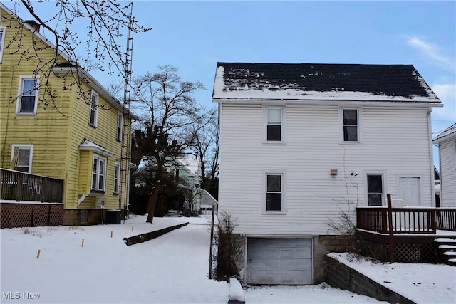 snow covered back of property featuring a garage