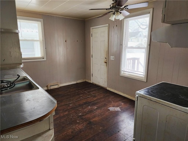 kitchen featuring dark wood-type flooring, sink, white range oven, wood walls, and ceiling fan