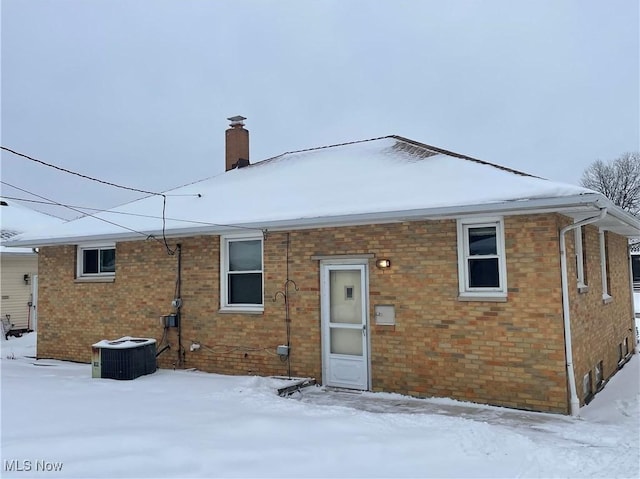 snow covered back of property with central AC