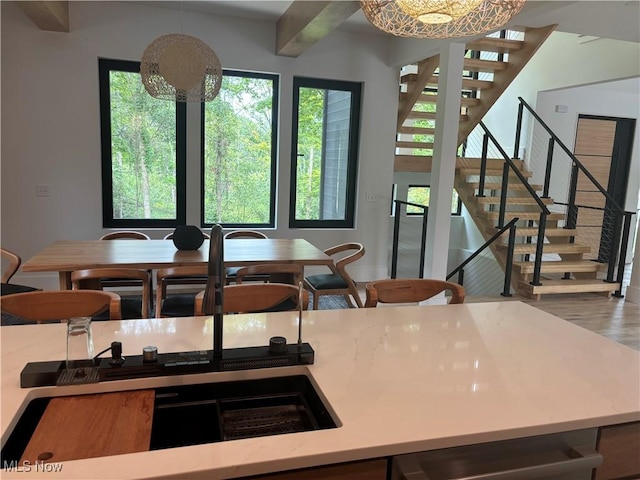 kitchen featuring decorative light fixtures, wood-type flooring, beamed ceiling, and a notable chandelier