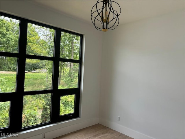 unfurnished room with a chandelier and light hardwood / wood-style flooring