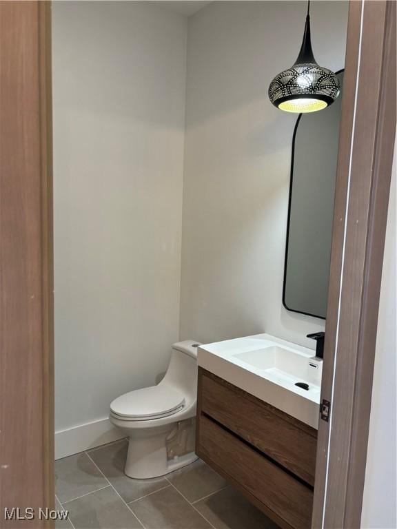 bathroom with toilet, vanity, and tile patterned flooring