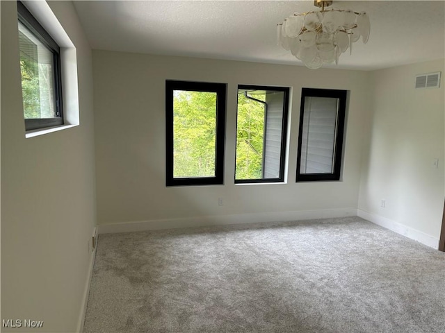 unfurnished room featuring light carpet and a notable chandelier