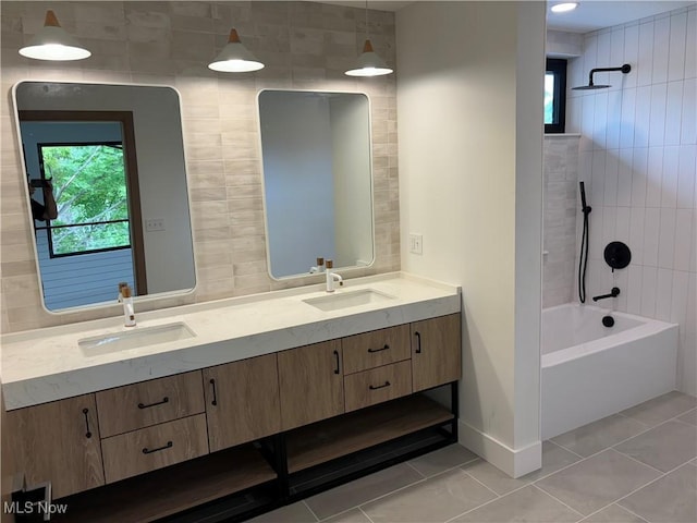 bathroom with a wealth of natural light, tile patterned flooring, tiled shower / bath, and vanity