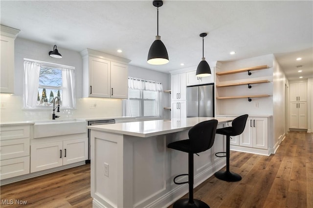 kitchen featuring stainless steel fridge, sink, white cabinetry, and a kitchen island