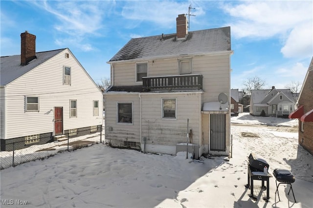 snow covered rear of property featuring a balcony