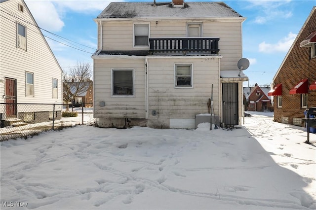 snow covered house featuring a balcony