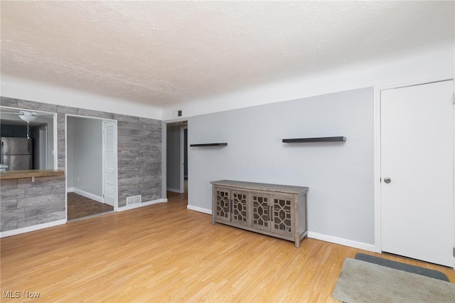 unfurnished living room with a textured ceiling and light hardwood / wood-style flooring