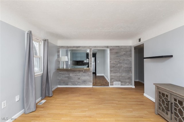 unfurnished living room featuring a textured ceiling and light hardwood / wood-style floors