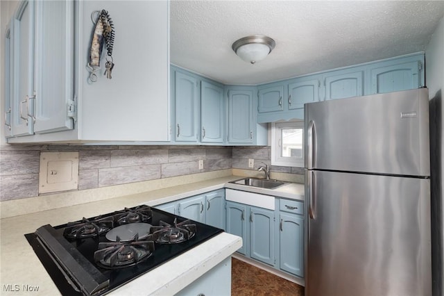 kitchen with sink, a textured ceiling, black gas stovetop, and stainless steel refrigerator