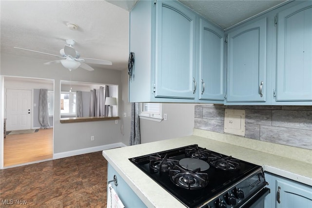 kitchen featuring ceiling fan, backsplash, black stove, and blue cabinets