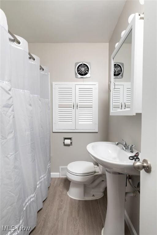 bathroom featuring toilet, curtained shower, and hardwood / wood-style floors