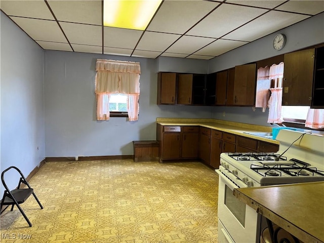 kitchen featuring white gas stove and dark brown cabinets