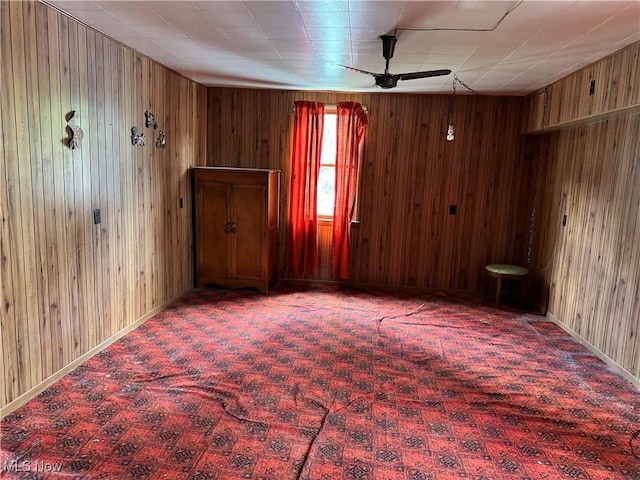 unfurnished room with ceiling fan and wood walls