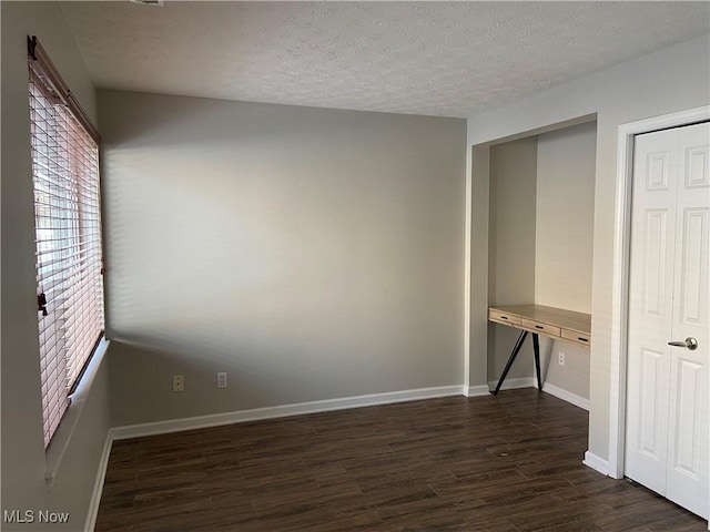 spare room with a textured ceiling and dark hardwood / wood-style flooring