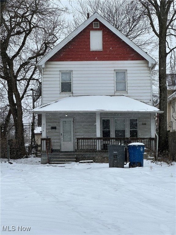 snow covered rear of property with a porch