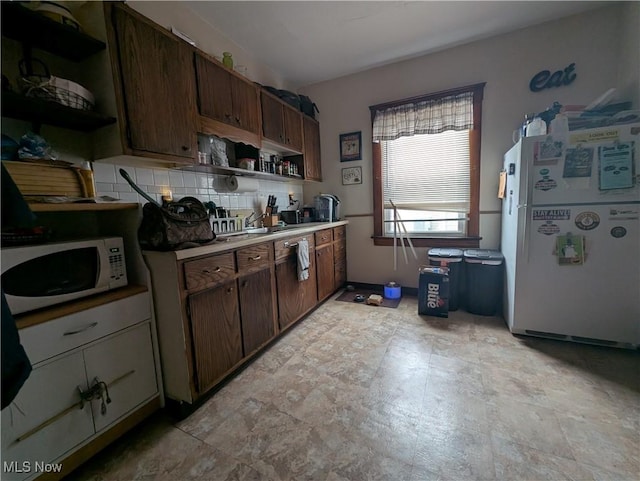 kitchen with backsplash, dark brown cabinetry, and white appliances