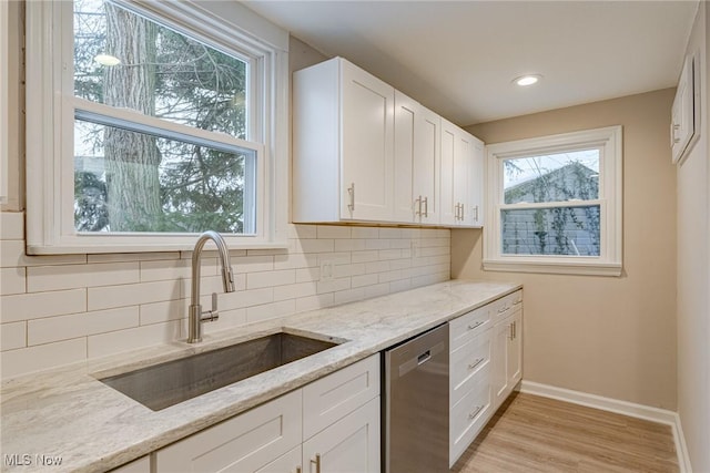 kitchen with dishwasher, decorative backsplash, sink, white cabinets, and light stone counters