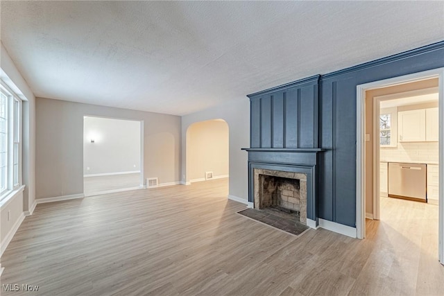 unfurnished living room featuring a fireplace, a textured ceiling, and light hardwood / wood-style flooring