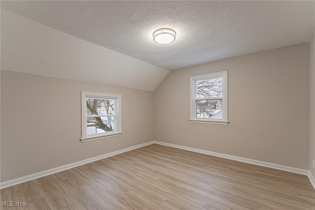 bonus room with vaulted ceiling, a healthy amount of sunlight, a textured ceiling, and light hardwood / wood-style floors