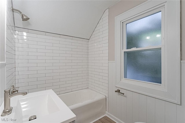 bathroom with lofted ceiling, tiled shower / bath combo, and sink