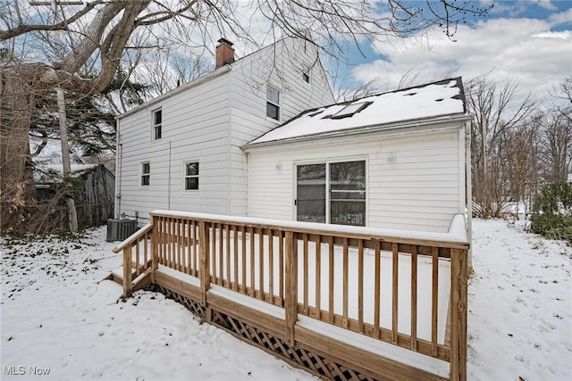 snow covered house with central AC and a deck