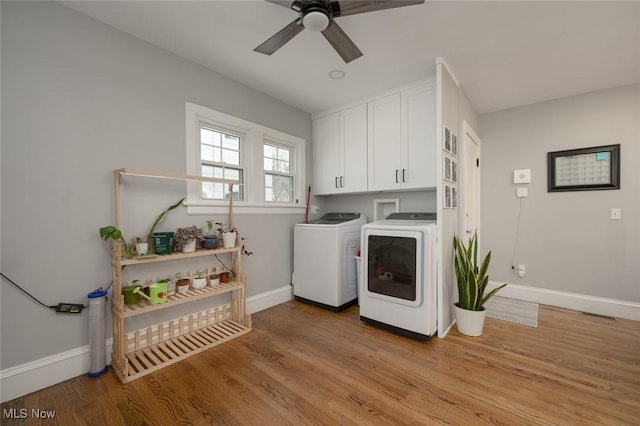 washroom featuring cabinets, washer and clothes dryer, light hardwood / wood-style flooring, and ceiling fan