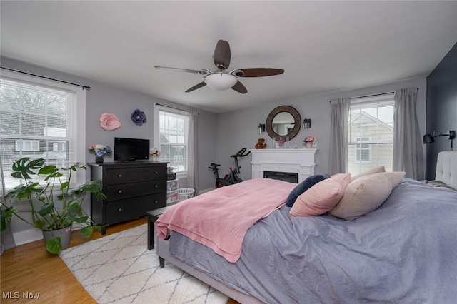 bedroom with light wood-type flooring, ceiling fan, and multiple windows