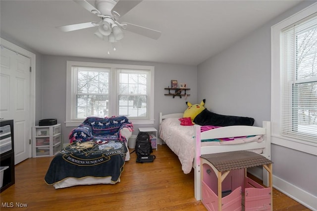 bedroom with ceiling fan, multiple windows, and wood-type flooring