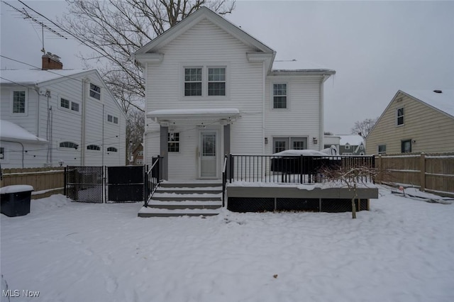 snow covered house featuring a wooden deck