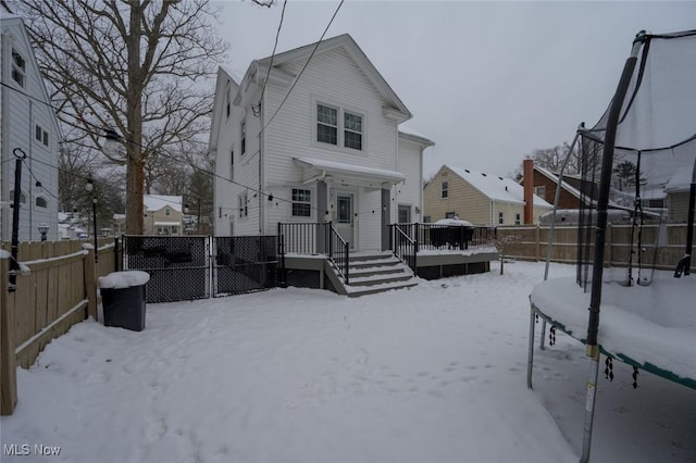 snow covered back of property with a trampoline