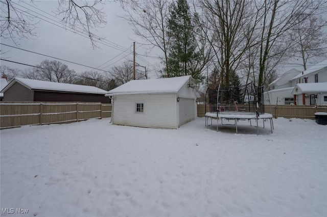 yard layered in snow with a trampoline and an outdoor structure