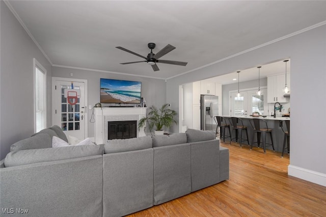 living room featuring ceiling fan, crown molding, light hardwood / wood-style flooring, and sink