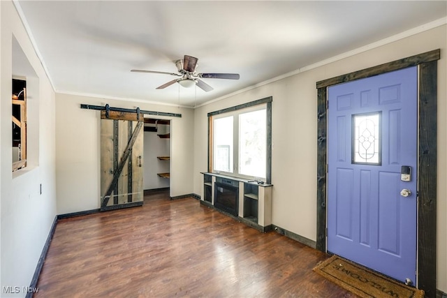 foyer featuring ceiling fan, dark hardwood / wood-style flooring, crown molding, and a barn door