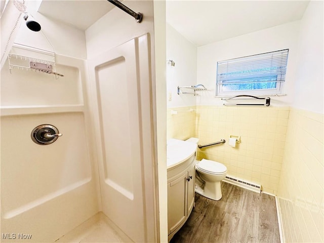 bathroom featuring baseboard heating, hardwood / wood-style floors, vanity, tile walls, and walk in shower