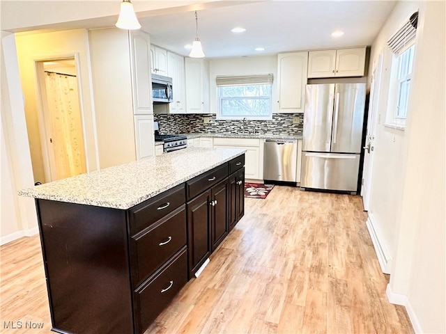 kitchen featuring decorative light fixtures, a center island, decorative backsplash, light hardwood / wood-style flooring, and stainless steel appliances