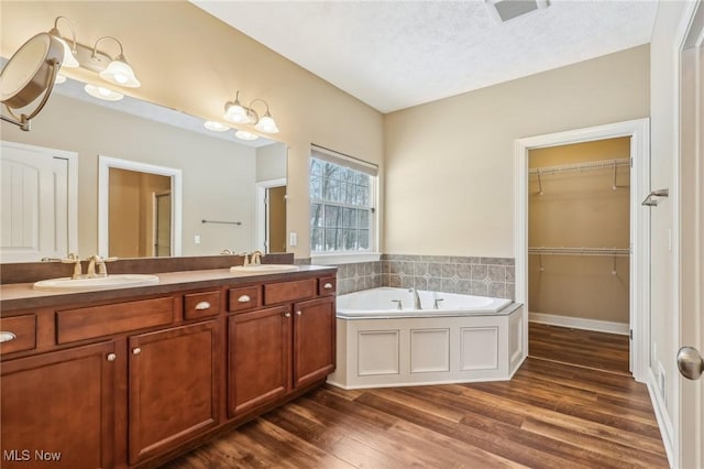 bathroom featuring wood-type flooring, a textured ceiling, a bath, and vanity