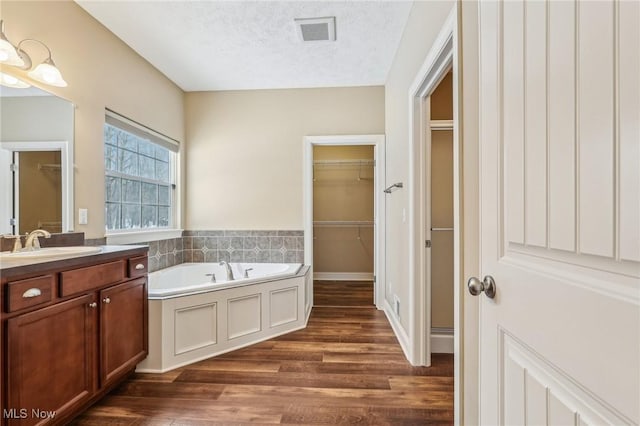 bathroom with a textured ceiling, a bathtub, hardwood / wood-style flooring, and vanity