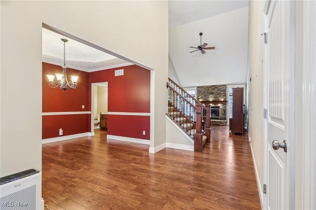 foyer featuring ceiling fan with notable chandelier, dark hardwood / wood-style flooring, crown molding, and a fireplace