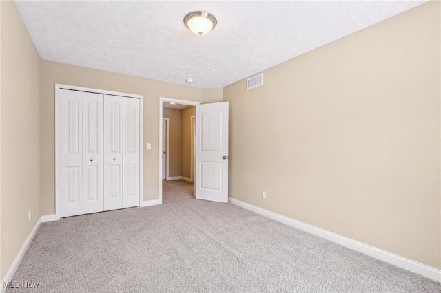 unfurnished bedroom with light carpet and a closet