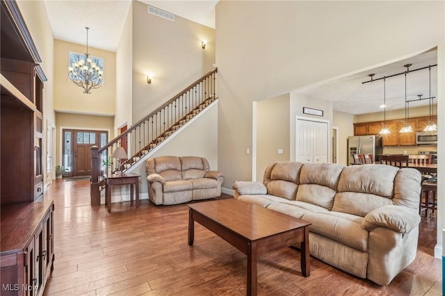 living room with an inviting chandelier, track lighting, a towering ceiling, and dark hardwood / wood-style floors