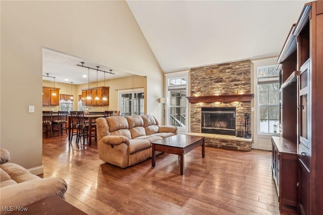 living room with dark wood-type flooring, a healthy amount of sunlight, a fireplace, and high vaulted ceiling